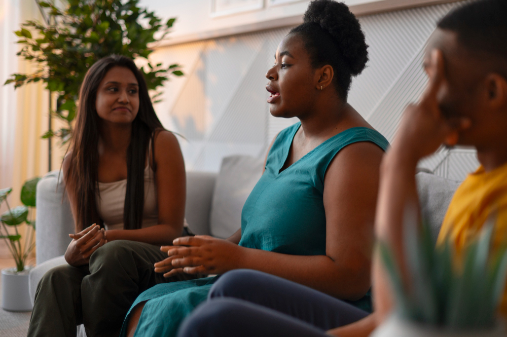 A woman expressing emotional fatigue in a group setting, symbolizing the support Bloom With Therapy provides to Californians feeling disconnected or overwhelmed.